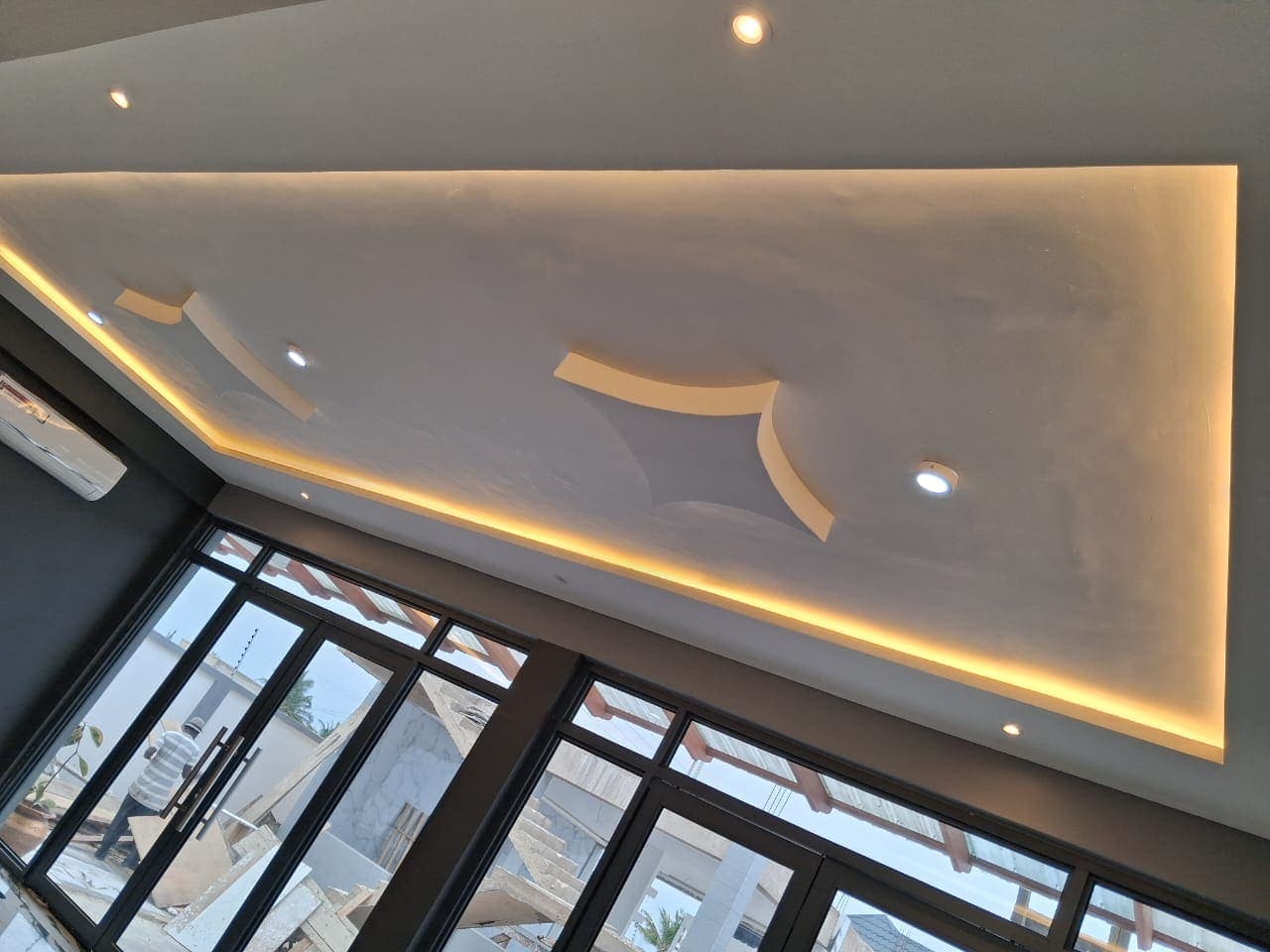 Angular POP ceiling panel with a star relief and warm cove lighting above the glazed frontage of an event hall in the Volta Region